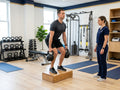 Strength coach supervising a client's kettlebell exercise in a rehabilitation gym