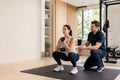Physical therapist supervising a client's strength exercise in a bright private home gym